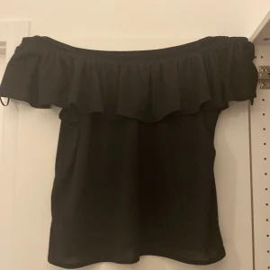 Svart offsholder tröja med volang  - Den är toppenskick, 10/10.  Inga hål eller nånting. Vet tyvärr inte storleken för lappen är inte kvar, Men skulle tro att den är i S. Skriv för frågor eller flera bilder🩷