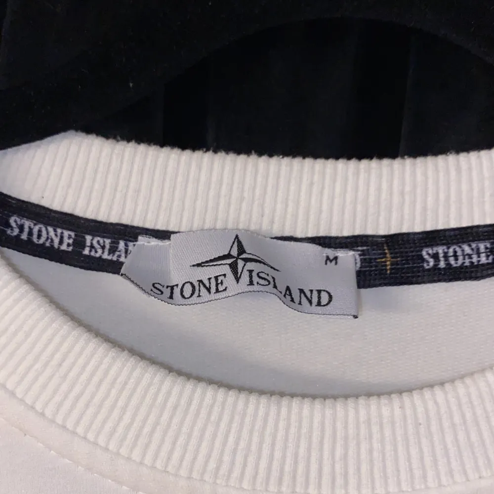 Säljer en stilren vit tröja från Stone Island. Den har en klassisk rund hals och långa ärmar. På bröstet finns en diskret svart logga och på ärmen sitter den ikoniska Stone Island-märket. Perfekt för både vardag och lite mer avslappnade tillfällen.. Tröjor & Koftor.