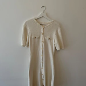 Vit stickad klänning från H&M - Säljer en superfin vit stickad klänning från H&M. Den har korta ärmar och knappar hela vägen ner, vilket ger en snygg och stilren look. Perfekt för både vardag och fest! 🖤