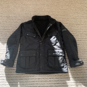 Barbour vår/höst jacka 158-164 (Barn XL) - Barbour höstjackan i ett svart fleece material bra värme nu till hösten. Finns fyra större fickor på utsidan, finns även möjlighet att spänna åt vi ryggen för ett mer slimmat utseende på jackan.