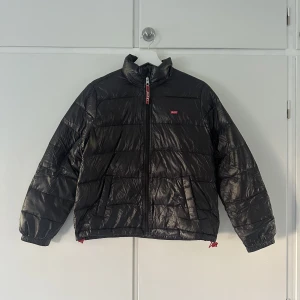 Jacka från Levi’s - Jacka från levi’s som är glansig med en logga. Den har tappat ”puff”. Den är liten i storleken men näst intill perfekt. Orginalpris 900-1000kr. Pris kan diskuteras💕