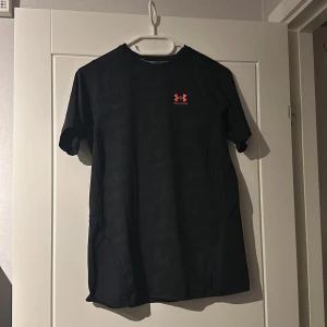 Under Armour träningströja - Säljer denna träningströja då den är för liten. Skicket är väldigt bra. Färgen är svart med röd/orange märke. Hör av dig vid frågor! Pris kan diskuteras vid snabb affär😊