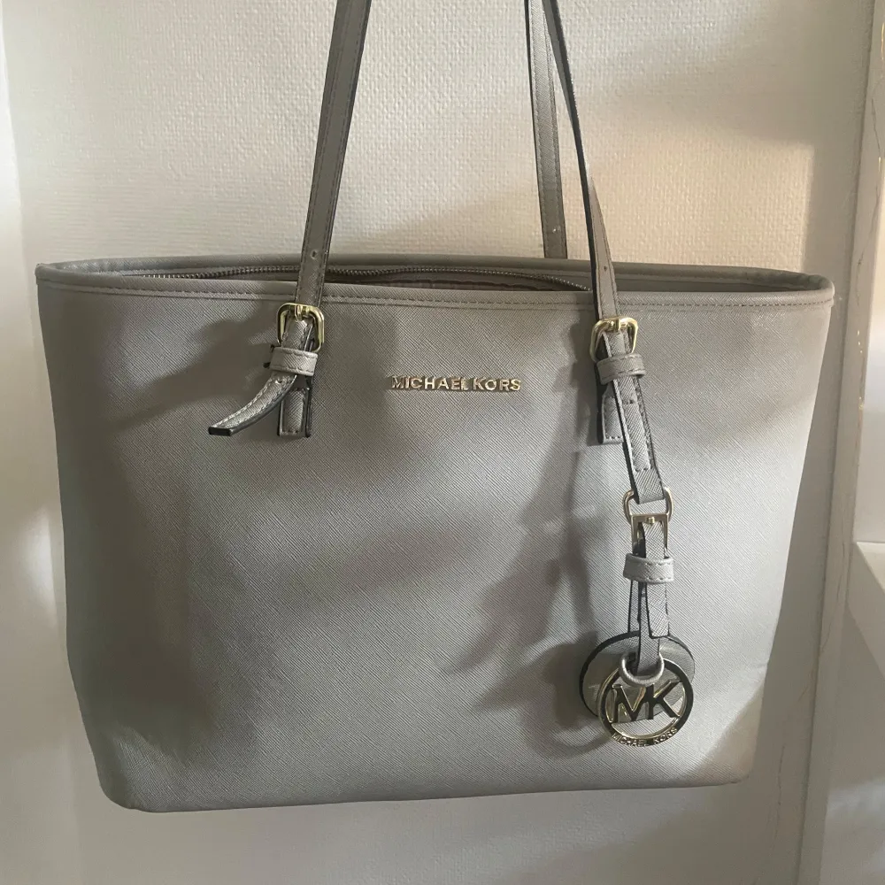 En grå stor Michael Kors väska som knappt är använd. Denna väska är köpt här på Plick för något år sedan och har några som defekter som knappt är synbara. Pris kan diskuteras. Tryck ej på köp direkt!. Väskor.