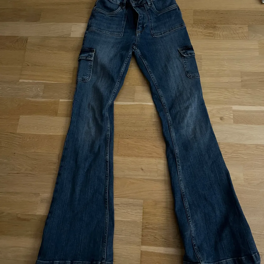 Säljer ett par snygga blå cargopants i jeansmaterial. De har praktiska fickor på sidorna och en skön passform. Perfekta för en avslappnad stil!. Jeans & Byxor.