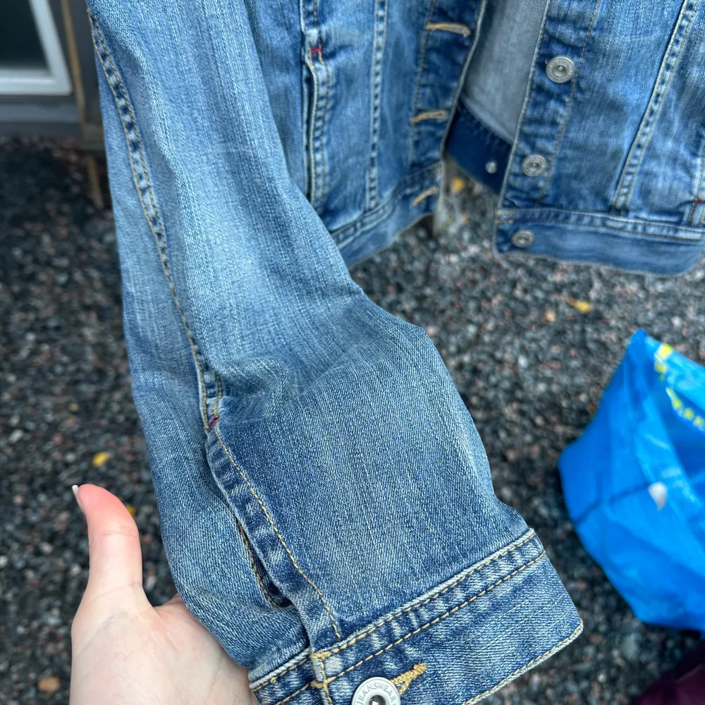 Säljer en snygg jeansjacka från Lindex i storlek 42. Den har en klassisk blå denimfärg. Jackan är långärmad och har knappar framtill samt två bröstfickor med knappstängning. Perfekt för vår och höst!. Jackor.