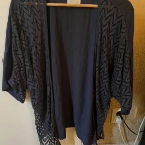 Svart kimono från Object - Säljer en snygg svart kimono från Object. Den har ett coolt mönster och är perfekt för att lägga till en extra touch till din outfit. Passar bra till både vardag och fest. Storlek 38.
