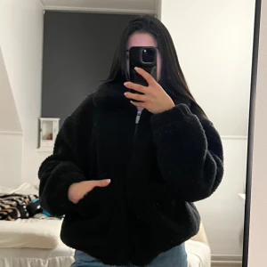 Svart teddyjacka med dragkedja - Mysig svart teddyjacka som är perfekt för både höst och vinter! Jackan har en dragkedja framtill och stora fickor för extra komfort. Den har en även en loose passform. Kontakta mig om ni har fler frågor, pris går att diskutera ❤️