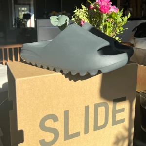 Yeezy Slide  - Yeezy Slide, Granit. Helt nya, oanvända. Skick 10/10. Originalbox och prislapp kvar. Står storlek 42, men dessa är kända för att vara väldigt små i storlek. Storlek 38-39 passar dessa 🪩