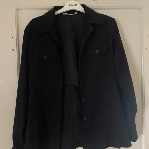 Svart jacka från Lindex - Säljer en stilren svart jacka från Lindex i storlek 36. Jackan har långa ärmar och knappar framtill. Perfekt för både vardag och lite finare tillfällen. 🖤