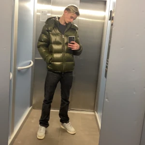 Grön pufferjacka från Polo Ralph Lauren - Säljer en snygg och varm grön pufferjacka från Polo Ralph Lauren. Jackan har en glansig yta och är perfekt för kalla dagar. Den har en dragkedja framtill och två praktiska fickor med dragkedjor. Perfekt för vintern! 🧥hör av er vid frågor!