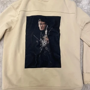 Beige hoodie med tryck från Limitato - Säljer en beige hoodie från Limitato med ett coolt tryck på ryggen. Den har en dragkedja framtill och justerbar huva med svarta snören. Insidan av huvan har ett mönstrat tyg. Perfekt för en fet outfit. Köpt på zgander för 4500kr inget kvitto tyvärr!