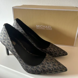 MICHAEL KORS ALINA FLEX PUMPS - Snygga, stilrena klackar ifrån MICHAEL KORS i storlek 37. Klackskorna är använda men i fint skick, en litet slitage på klacken men verkligen inget som syns på eller om man inte tittar väldigt nära. Nypris 1250:-