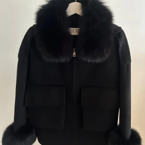 STEPHANIE JACKET SVART - Superfin höst kappa ifrån FURSTOCKHOLM i storlek S. Kappan är i jättebra skick. Dem fåtal gånger jag använt den har jag använt den sparsamt och när pälsen blivit fuktig har jag tagit hand och fönat den därav behålls fluffet i pälsen. Nypris 1640:-
