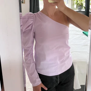 Oneshoulder blus med puffärm - Lila oneshoulder blus med puffärm från ginatricot. Bra skick.