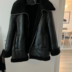 Svart pilotjacka med teddy  - Svart pilotjacka med teddy.  Storlek: EU 50