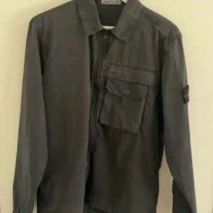 Stone island jacka - Tja!, Säljer nu den här skit feta stone island overshirten!. den är i färgen svart och i storlek s. Den är köpt ny för 4,5k men kvitto finns ej. Ändas tagsen och overshirten följer med. Den är i sjukt bra skick och inga defekter!. Mvh::Oscar!!!!!!!!.