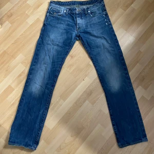 Blå jeans från G-Star - Säljer ett par snygga blå jeans från G-Star, modell RAW 3301. De har en klassisk femficksdesign med en cool sliten look. Perfekta för en avslappnad stil!