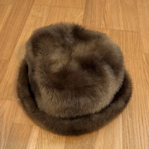 Brun pälsmössa från House of Saki - Säljer en superfin brun fuskpälsmössa från House of Saki. Den har en mjuk och fluffig känsla, samt håller dig verkligen varm på vintern🤎