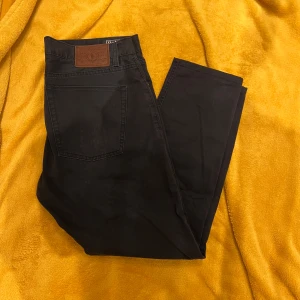 Ralph lauren jeans blå 32/34 - Snygga svarta jeansbyxor från Polo Ralph Lauren med klassisk femficksdesign och knappgylf. Perfekta för en stilren look.