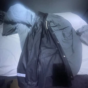 Svart regnjacka från 157 - Säljer en stilren svart regnjacka från 157. Jackan har knappar framtill (möts helst up i Gbg)