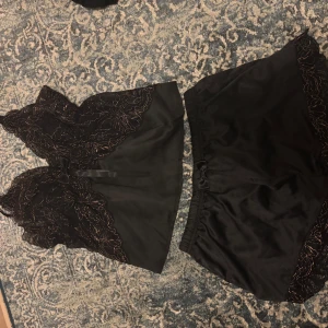 Svart satinpyjamas med spetsdetaljer - Svart satinpyjamas med guldiga spets detaljer, helt ny aldrig använt💗💗💗
