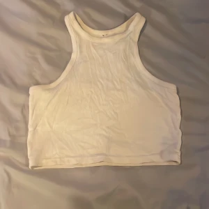 Vit ribbad linnetopp - Säljer en stilren vit ribbad linnetopp. Perfekt för varma sommardagar eller som ett basplagg i garderoben. Toppen är ärmlös och har en klassisk rund halsringning.