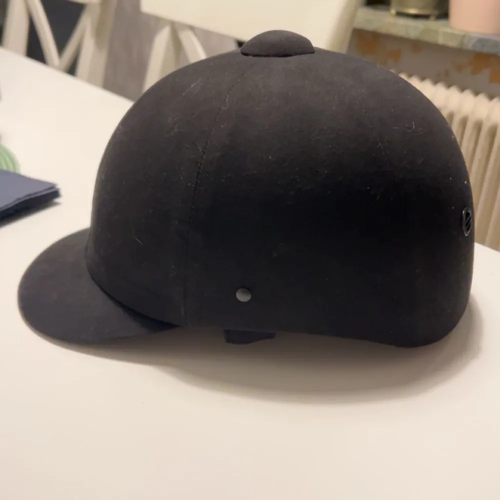 Säljer en klassisk svart ridhjälm från CRW. Hjälmen har en rund form med ventilationshål på sidorna och en liten knapp på toppen. Perfekt för ridning och säkerhet. . Muu.