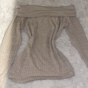 Beige offshoulder tröja från BikBok - Säljer en stilren beige offshoulder tröja från BikBok. Tröjan är ribbad och har långa ärmar, perfekt för en trendig look. Passar utmärkt till både jeans och kjol. Hör av dig vid intresse!