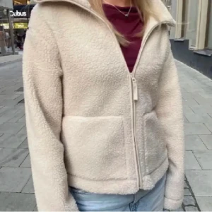 Beige teddyjacka hm - Mysig beige teddyjacka med dragkedja framtill. Perfekt för kyliga dagar med sin fluffiga och varma design. Jackan har en hög krage och två praktiska fickor.