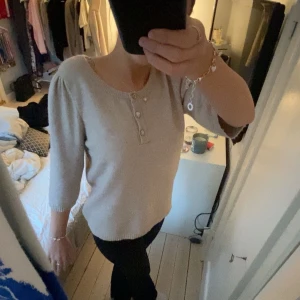 Beige tröja med glittriga knappar från Isolde - Säljer en stilren mörk beige tröja från Isolde med trekvartsärm och glittriga knappar framtill. Tröjan har en rund halsringning och är tillverkad i ett mjukt material. Säljer den på grund av att den är förstor. På sista bilden ser man att knappen högst upp har tappat några diamanter, vilket inte syns på långt håll. Tycker verkligen den är så fin och skön. Pris går absolut att diskutera. 💓💓