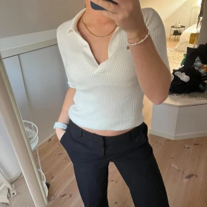 Vit ribbad topp från NA-KD - Stilren vit ribbad topp från NA-KD med krage och v-ringning. Toppen har korta ärmar och en figurnära passform. Storlek XXS men skulle säga att den är stor i storleken då jag vanligtvis har storlek XS/S! 