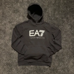 Svart EA7 hoodie: Riktigt Bra Sick - Snygg svart hoodie från Emporio Armani med EA7-logga på bröstet, bara hör av er vid frågor. Storlek: M