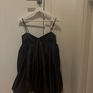 Svart klänning med smala axelband - Svart klänning från HM! Perfekt för festliga tillfällen. Den är oanvänd med prislappen kvar! 