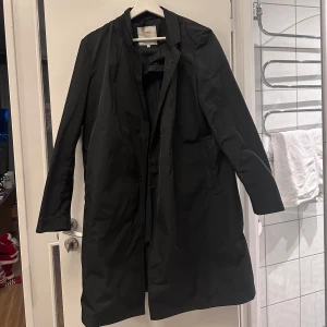 Svart kappa från Boomerang - Elegant svart kappa från Boomerang i storlek S. Kappan har en stilren design med långa ärmar och knappar framtill. Perfekt för både höst och vår.