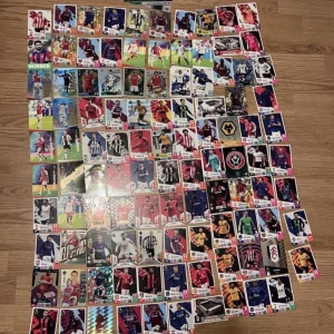 Fotbollskort  - En samling av fotbollskort med olika spelare och lag. Kortens design varierar med färgglada bilder och laglogotyper. Perfekt för samlare eller fotbollsfans som vill utöka sin kollektion.