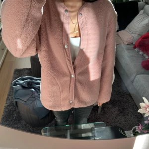 Rosa teddyjacka med quiltad insida - Mysig rosa teddyjacka med quiltad insida och tryckknappar. Perfekt för kyliga dagar med sin vändbara design. Jackan har en rund hals och långa ärmar. Super söt men passar inte mig, inget märke och ingen strl, men gissar p strl S-M Jätte skön och finns små små defekter men inget man tänker på! 🩷🩷