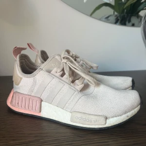 Adidas NMD sneakers i ljusrosa - Snygga Adidas NMD sneakers i en ljusrosa nyans med vita och rosa detaljer. Skorna har en bekväm passform med snörning och en dämpande sula. Perfekta för en avslappnad stil.
