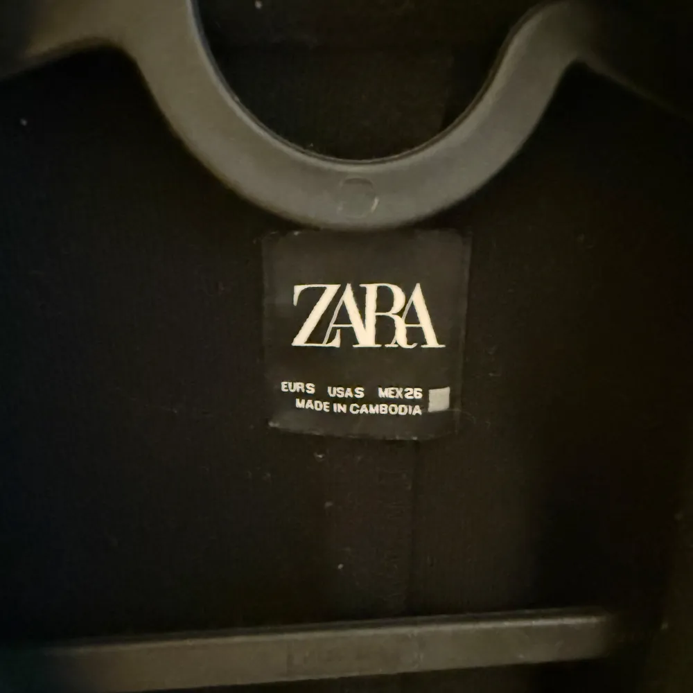 Stilren svart lång kappa från Zara med långärmad design. Kappan är i storlek S men är lite mindre i storleken. Takit.