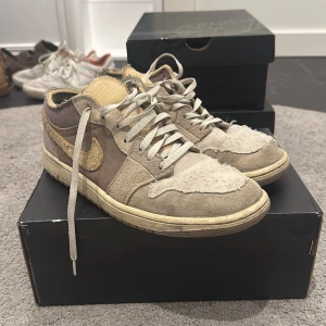 Air Jordan 1 low Craft  - Säljer ett par Nike sneakers i beige och brunt med snörning. Skorna har en klassisk design med Nike-logga på sidan. Skorna är i bra skick men på bilderna är dem lite smutsiga men de är såklart bara att tvätta bort. Nypris 1500kr