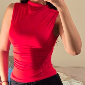 Röd ärmlös topp - Snygg röd ärmlös topp med en tight passform. Perfekt för en somrig look eller en kväll ute. Enkel och stilren design som passar till många olika outfits.