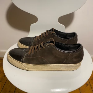 Lanvin storlek 45 - Säljer dessa snygga bruna lanvin i storlek us 10 motsvarar eu 45.                                               Dem är välanvända men har mycket liv kvar. Hälen är lite ned trampad men inget som påverkar användningen. Glanset där fram på skorna är inte jätte glansigt längre men det borde gå att fixa med lite sko fett. Ändarna på skosnörena har tappat plasten.                           Du som köpare får avgöra skicket på bilderna.(skickar gärna mer bilder om så önskas) Hör av dig vid frågor!