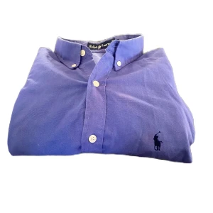 Blå skjorta från Ralph Lauren - Snygg blå skjorta från Ralph Lauren med klassisk krage och knappar framtill. Den har en broderad logotyp på bröstet som ger en stilren touch. Perfekt för en elegant look.