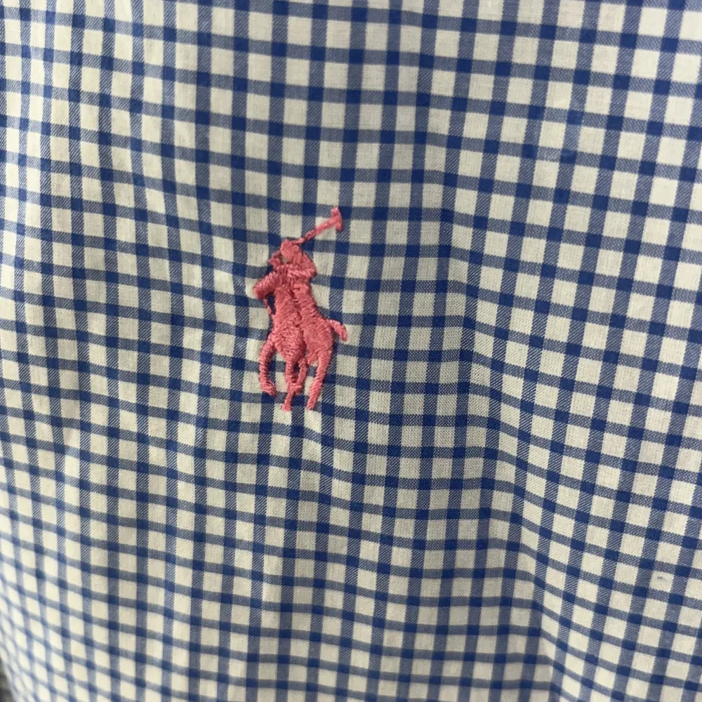 Säljer en snygg blå och vit rutig skjorta från Ralph Lauren. Skjortan har långa ärmar och klassiska knappar framtill. Den är i bomull och har en broderad rosa logga på bröstet. Bra skick, 8/10. Lång modell på skjortan så passar bra om du är lång. M/L. Skjortor.