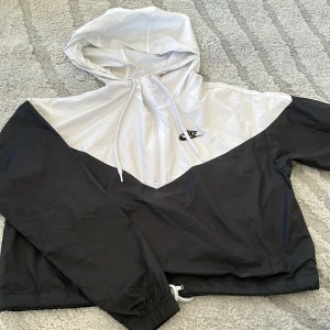 Vindjacka nike - Svart vit vindjacka från märket nike. Har snörning nertill vilket gör att man kan dra åt jackan