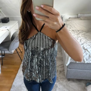 Glittrig topp - Säljer en super fin glittrig topp, med knytning runt halsen, med slitts bak i ryggen, super fint skick!💕