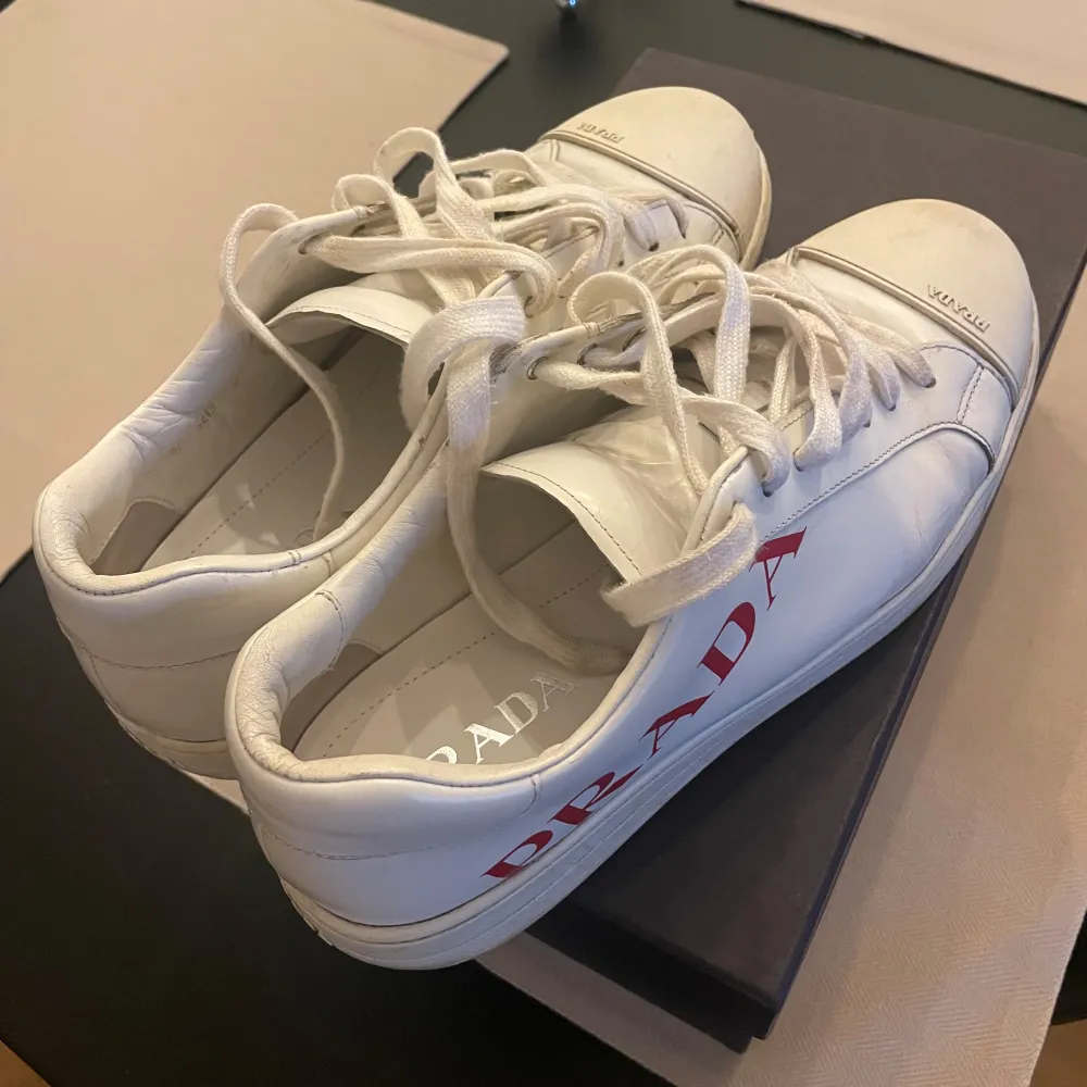 Vita Prada sneakers. Använda men i gott skick! Cond: 7/10 Size: 9 (passar 44) Box ingår, pris kan diskuteras . Skor.