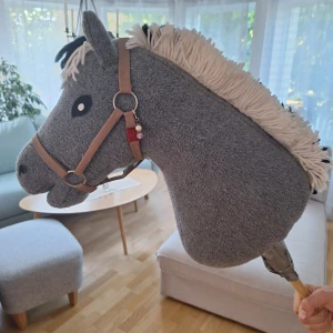 Käpphäst - En handsydd grå käpphäst med vit och svart man. Grimman på bilden följer med och ett blå möstrat täcke. Den är smidig att ta med, men jag rekommenderar den till lute större barn. Den är noga sydd och i bra skick. Man kan hämta söder om stan i Sthlm.