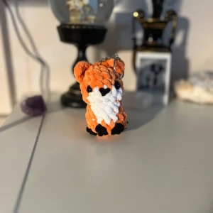 Nyckelring med räv i pärlor - Supergullig nyckelring formad som en räv, gjord av små pärlor i orange, vit och svart. Perfekt att hänga på väskan eller använda som nyckelring för att ge lite extra stil. Den är handgjord och har en fin glans i pärlorna.