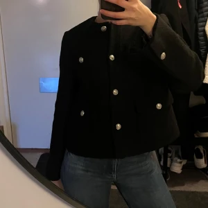 Svart kavaj  - Säljer en stilren svart kavaj från MQ. Den har en klassisk design med silverfärgade knappar och två fickor framtill. Använd max tre gånger!🖤🖤