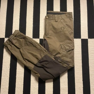 Gröna byxor från Chevalier - Säljer ett par mörk gröna frilufts/jakt byxor från Chevalier. Byxorna har flera praktiska fickor.  Perfekta för utomhusaktiviteter och äventyr! Om storlek 50 inte säger dig något, så mäter jag på  ungefär L34 och W33-34. Nypris: 1200kr 